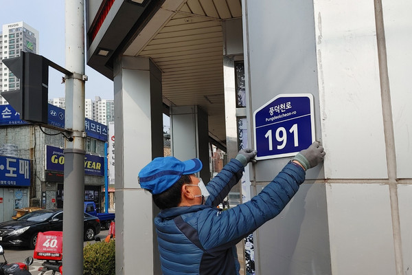 사진) 관내 한 건물의 도로명주소 번호판을 새로 설치하고 있는 모습ⓒ경기타임스
