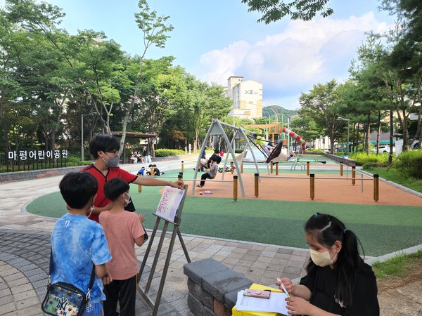 사진) 마평어린이공원을 이용한 시민과 어린이들이 이용자 만족도 조사 패널에 스티커를 붙이고 있는 모습ⓒ경기타임스